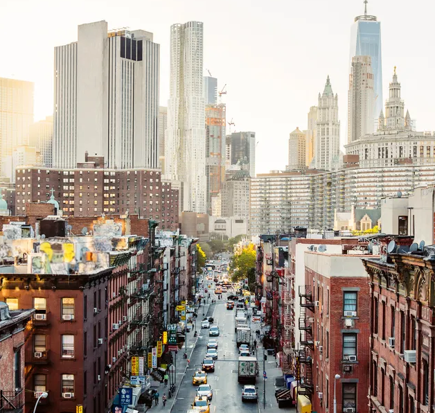 Bustling downtown city street with high-rises at sunset.